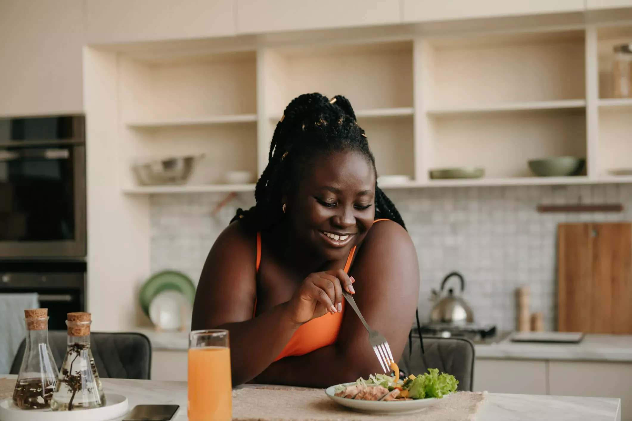 Young joyful woman eating lunch at kitchen counter